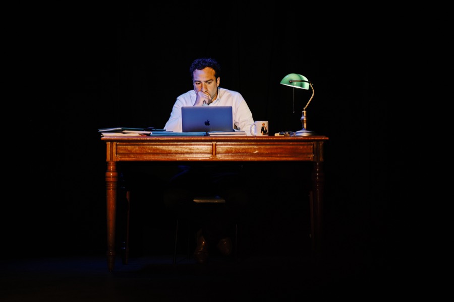 À son bureau, la nuit, sous une lampe de banquier verte
